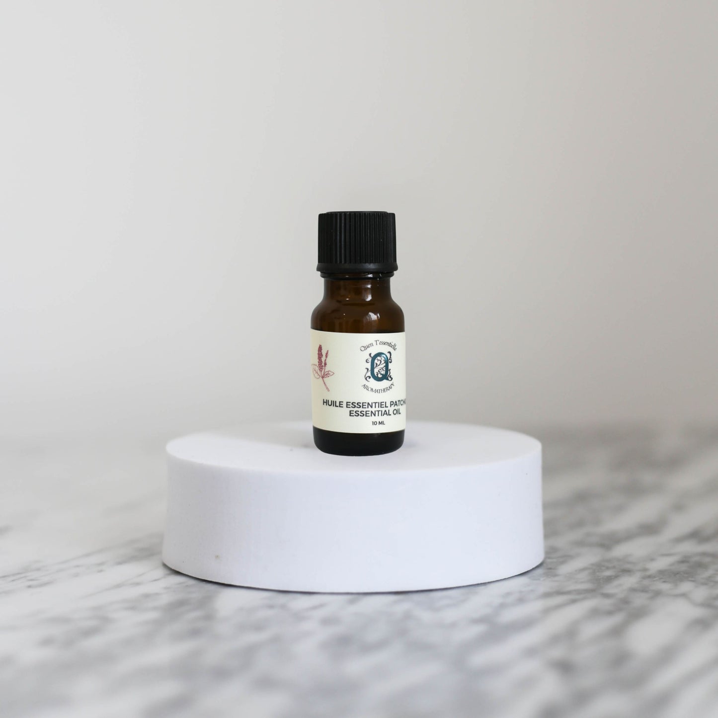 Small amber glass bottle of Patchouli essential oil with a label on a white marble surface.