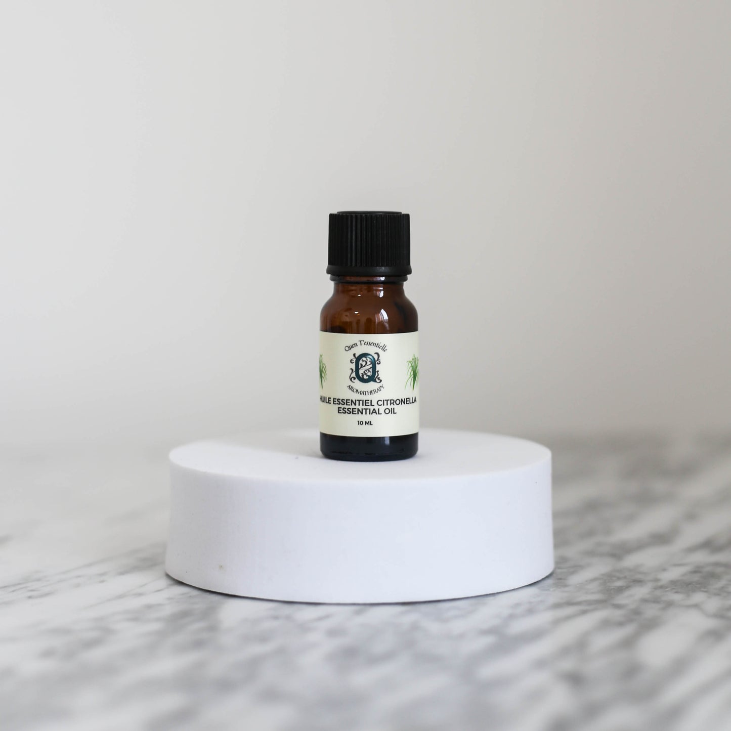 Citronella Essential Oil 10ml bottle by Quen T’essentielle Aromatherapy, displayed on a white pedestal with a minimalist background – natural insect repellent and mood-boosting essential oil.